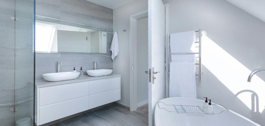 Sleek contemporary bathroom with bathtub and twin sinks, showcasing minimalist design and luxury.